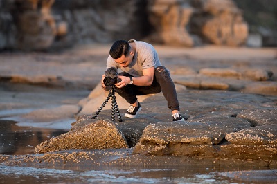 man on the beach taking a picture of the sunset