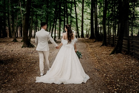 wedding photo of the bride and groom walking in the woods