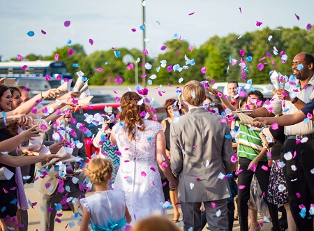 a wedding photo of people throwing confetti to the newly weds