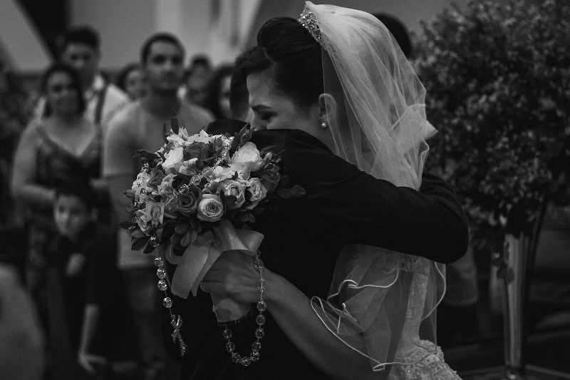 a black and white wedding photo of an emotional bride hugging the groom